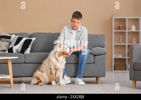 Adolescente con cane pastore australiano seduto sul divano di casa Foto Stock