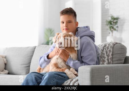 Adolescente con cane pastore australiano seduto sul divano di casa Foto Stock