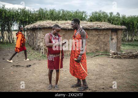 (240822) -- NAROK, 22 agosto 2024 (Xinhua) -- gli abitanti del villaggio Maasai comunicano in un villaggio nella riserva nazionale Masai Mara a Narok, Kenya, il 21 agosto 2024. I Maasai, una delle principali tribù del Kenya, sono principalmente sparsi nelle parti sud e sud-ovest che confinano con la Tanzania. La tribù vive ancora in modo nomade. Il loro insediamento copre le destinazioni turistiche famose in tutto il mondo della riserva nazionale Masai Mara e del Parco nazionale del Serengeti. Con lo sviluppo dell'industria turistica locale, i Maasai hanno aperto i loro villaggi per abbracciare i turisti, come un modo per aumentare il loro reddito mentre ma Foto Stock