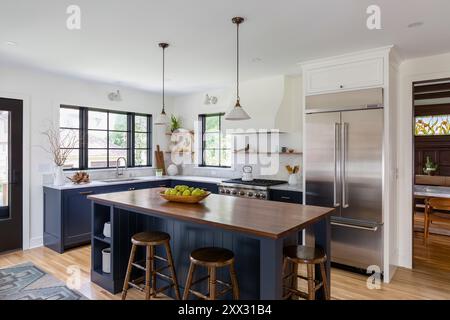 Cucina con armadi blu, ripiani in marmo bianco e ripiani in noce Foto Stock