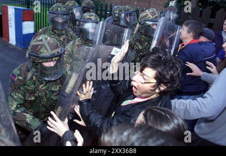 Foto del file del 03/09/01 di una donna protestante respinta dai soldati in equipaggiamento antisommossa, mentre i bambini sono scortati alla Holy Cross Primary School nel distretto repubblicano di Ardoyne a Belfast, Irlanda del Nord, il primo giorno del nuovo mandato scolastico. C'erano timori a Stormont nel 2001 che l'escalation della disputa sulla Santa Croce potesse portare ad altre scuole bloccate per rappresaglia, rivelando file appena declassificati. Data di pubblicazione: Giovedì 22 agosto 2024. Foto Stock