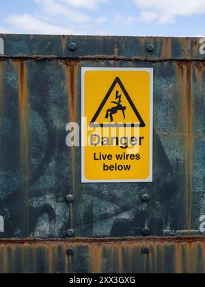 Pericolo di cavi sotto il cartello di avvertimento giallo con logo, su un ponte ferroviario a Blisworth Arm, Northamptonshire, Regno Unito Foto Stock