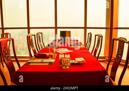 Bangkok, Tailandia - 11 febbraio 2024: Interni moderni e accoglienti di colore rosso, servizi da pranzo vuoti. Cena di lusso all'hotel Baiyoke Sky. Bangk Foto Stock