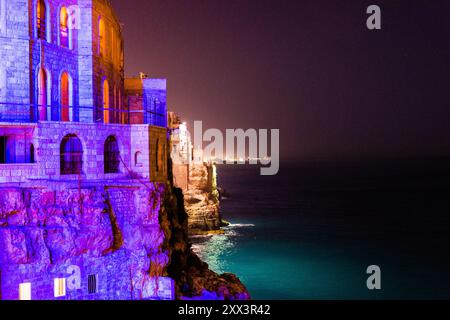 Vista degli edifici sul mare della città di Polignano a Mare illuminati con vari colori Foto Stock