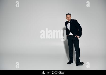 Un uomo in un smoking si trova di fronte a un semplice sfondo bianco. Foto Stock