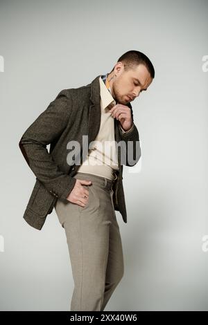 L'uomo regola il colletto in tweed blazer e il kakis sul grigio. Foto Stock