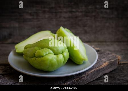 Zucca d'India verde fresca, cayote su fondo di legno, (Sechium edulis) Foto Stock