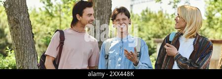 Tre giovani amici, vestiti con abbigliamento casual, passeggiano in un parco in una giornata di sole. Foto Stock