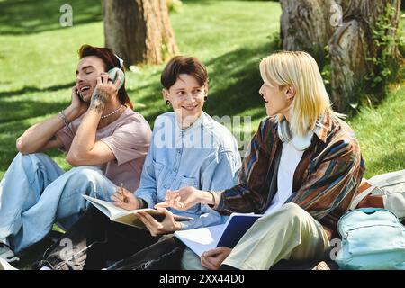 Tre giovani amici, vestiti in modo informale, condividono un momento di risate e conversazione mentre sono seduti in un parco erboso. Foto Stock