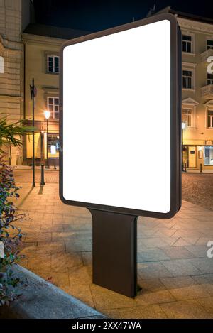 Mockup vuoto di Billboard verticale Outdoor su City Street di notte. Poster pubblicitario Lightbox sul marciapiede Foto Stock