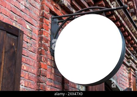 Bianco bianco Mockup di Street Store cartello Vintage su una vecchia parete di mattoni rossi. Segno rotondo vuoto per la vendita al dettaglio per logo o marchio Foto Stock