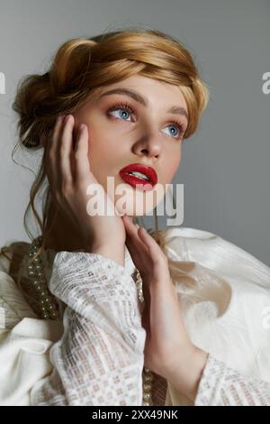 Una giovane donna con una camicetta bianca guarda verso l'alto con desiderio, toccando delicatamente il suo viso. Foto Stock