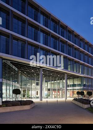 Vista verso l'ingresso principale e la reception al tramonto. Building 1180, Reading, Regno Unito. Architetto: Spratley + Partners, 2022. Foto Stock