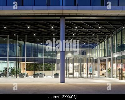 Vista verso l'ingresso principale e la reception al tramonto. Building 1180, Reading, Regno Unito. Architetto: Spratley + Partners, 2022. Foto Stock