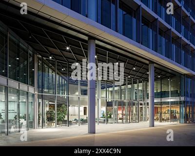 Vista verso l'ingresso principale e la reception al tramonto. Building 1180, Reading, Regno Unito. Architetto: Spratley + Partners, 2022. Foto Stock