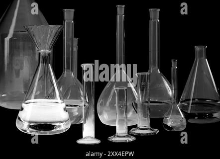 Ampia gamma di vetreria da laboratorio parzialmente riempita con retro nero Foto Stock