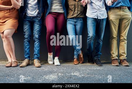 Gruppo, gambe e uomini d'affari sul muro per colloqui, hr o concorso di reclutamento alla startup creativa. Scarpe, assunzione di lavoro o attesa in fila all'aperto Foto Stock