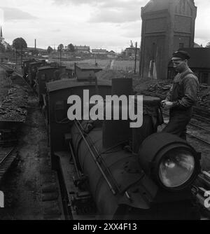 Effettivo 21-1949: Vestfold diventa a scartamento ampio nel sito della stazione di Drammen, le locomotive a scartamento ridotto erano in piedi mentre il treno di apertura era salutato da tutta Vestfold. Il pulitore per locomotive Ivar Opheim avvolge i teloni intorno ai camini per proteggerli dalla pioggia e dai detriti autunnali. E' concepibile che alcune delle migliori di queste locomotive saranno vendute al Nord Africa. Foto; Sverre A. Børretzen / Aktuell / NTB ***FOTO NON ELABORATA*** il testo dell'immagine viene tradotto automaticamente Foto Stock