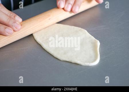 Impasto arrotolato a mano con un rullo di legno. Foto Stock