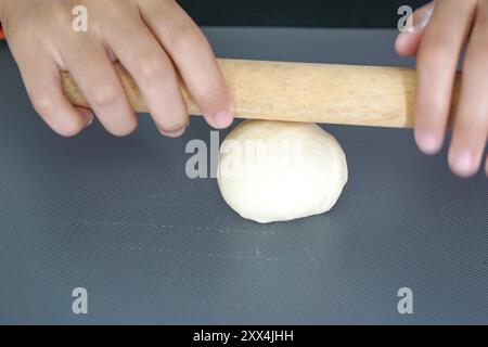 Impasto arrotolato a mano con un rullo di legno. Foto Stock