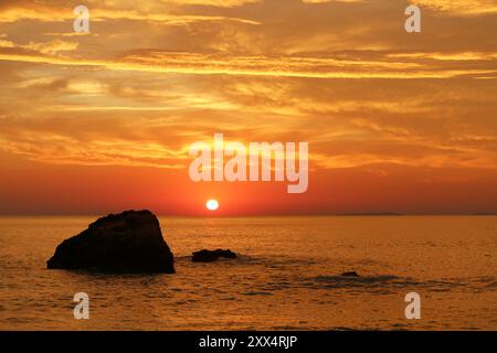 Cielo arancione sul Mar Ionio con rocce al tramonto (vicino a Preveza, Grecia) Foto Stock