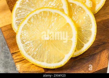 Limoni a fette gialli crudi organici su un tagliere Foto Stock
