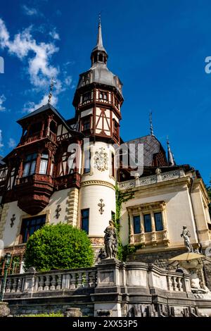 Un bellissimo castello storico di Peles con architettura ornata e statue sotto un cielo azzurro limpido in Romania Foto Stock
