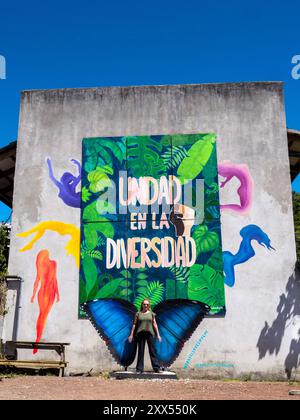 Donna in piedi davanti a Graffiti sul lato dell'edificio Foto Stock