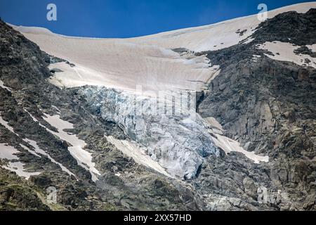 vista di un piccolo ghiacciaio che si scioglie coperto di neve e polvere marrone del sahara sul monte bianco in estate al cielo blu Foto Stock