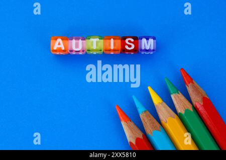 Cubi che formano la parola autismo e matite colorate Foto Stock