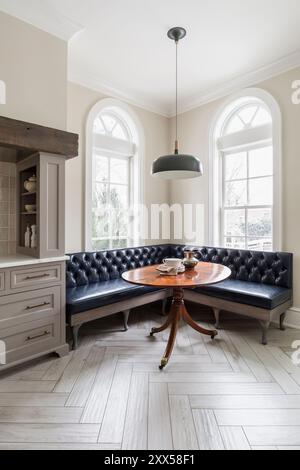 Cucina con banquette ad angolo in pelle navy scura e tavolo antico Foto Stock