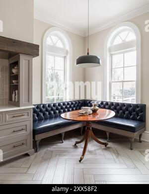 Cucina con banquette ad angolo in pelle navy scura e tavolo antico Foto Stock