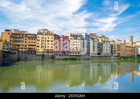 Antiche case italiane dai colori chiari lungo le calme acque del fiume Arno nella parte storica di Firenze (Firenze), Italia Foto Stock