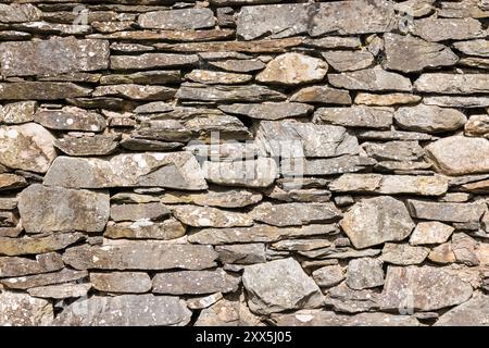 Dettaglio del muro di pietra a secco su un antico edificio nel Lake District inglese, Regno Unito. Pattern full frame, texture o sfondo. Foto Stock