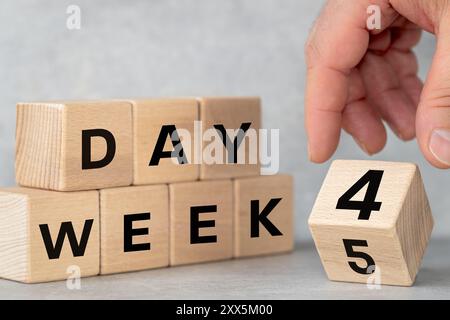4 giorni settimanali, concetto di business. Cubo di legno girevole a mano da 5 a 4. Simbolo di riduzione della settimana lavorativa. Scritto 4 giorni di settimana su isolati, bellissimo grigio m Foto Stock