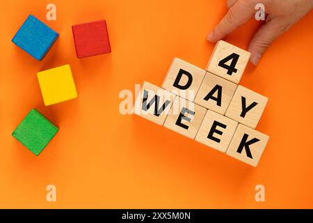 4 giorni settimanali, concetto di business. Mano mette un cubo di legno con il numero 4 a Words Day Week. Simbolo della settimana lavorativa abbreviata. Scritto 4 giorni a settimana su blocchi, Bea Foto Stock