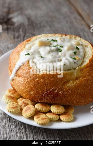 Primo piano verticale di stile New England Clam Chowder in ciotola di pane, con ostriche di cracker e copia dello spazio. Foto Stock