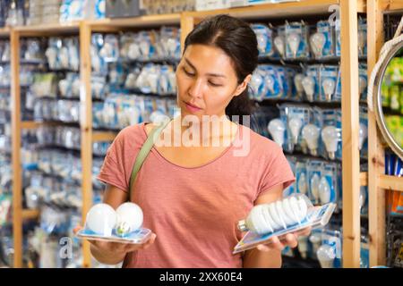 La donna ha scelto la lampada a risparmio energetico presso il negozio di hardware Foto Stock