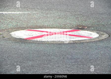 Segnaletica stradale circolare su asfalto con una "X" rossa, bandiera inglese o simbolo St George Cross Foto Stock