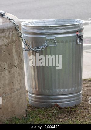 il contenitore dei rifiuti è incatenato al post Foto Stock