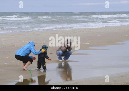 La famiglia visita la spiaggia sabbiosa in una giornata ventosa all'inizio della primavera a Blokhus, Jutland, Danimarca, Scandinavia, Europa Foto Stock