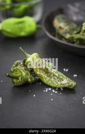 Porzione di Pimientos de Padron su un rustico di lastre di ardesia, il fuoco selettivo di close-up shot Foto Stock