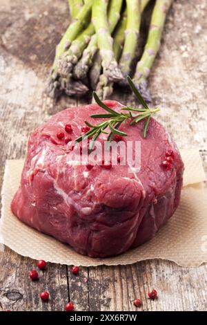 Bistecca cruda con asparagi su legno Foto Stock