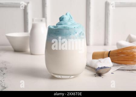 Bicchiere di dalgona blu matcha latte, chasen e cucchiaio sul tavolo Foto Stock