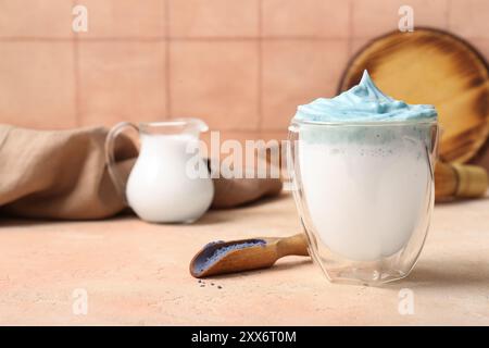 Bicchiere di latte matcha dalgona blu e paletta con matcha in polvere sul tavolo, primo piano Foto Stock