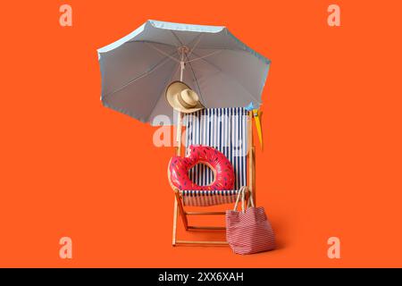 Sdraio, ombrellone, cappello, borsa e anello gonfiabile su sfondo rosso Foto Stock