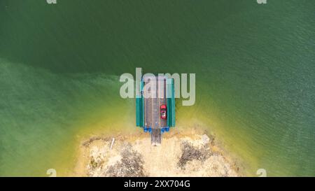 Vista aerea di traghetti locali che trasportano auto, moto e persone attraverso un fiume nella provincia di Kanchanaburi, Thailandia. Foto Stock