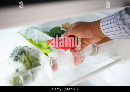 contenitori di plastica con frutta diversa in un frigorifero aperto. Foto Stock