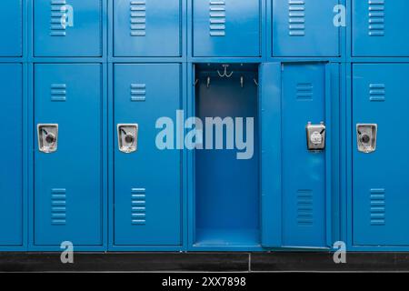 Un unico armadietto di metallo blu vuoto lungo un corridoio non delimitato in una tipica scuola superiore degli Stati Uniti. Nessuna informazione identificabile inclusa e nessuno nella ha Foto Stock