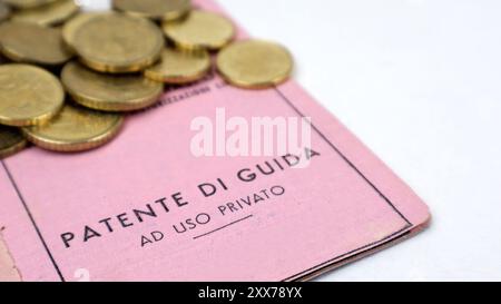 Patente di guida documento di identità rosa vecchio tipo isolato su primo piano e sfondo con monete in euro. Foto Stock